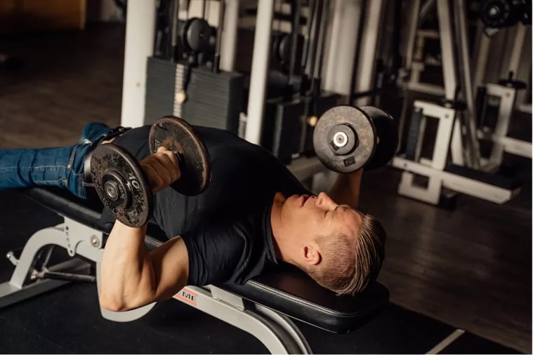 workout methods to attain the exercise high - man doing dumbbell press on bench